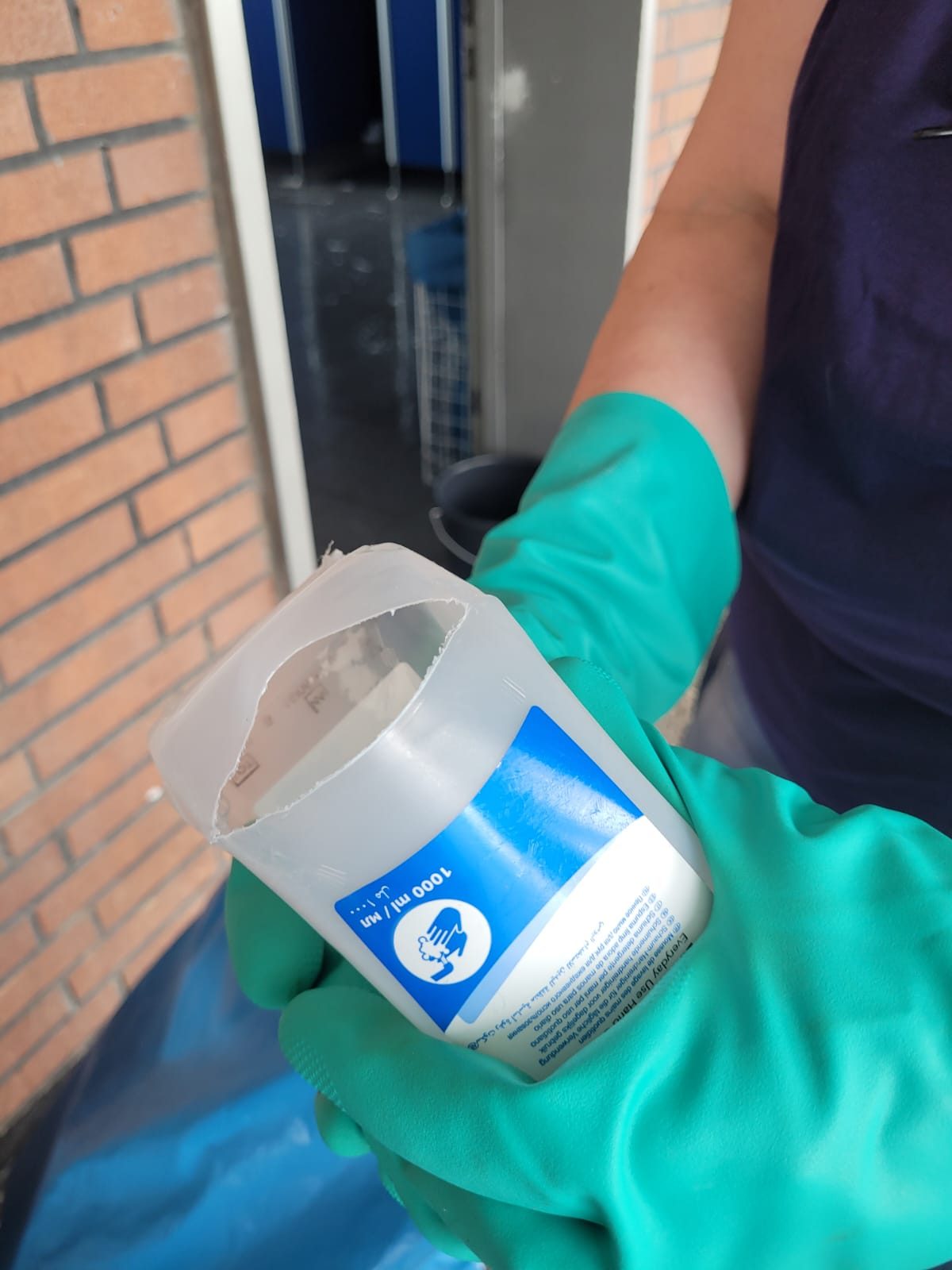 Eine Hand im grünen Handschuh hält eine aufgeschnittene Seifenkartusche.